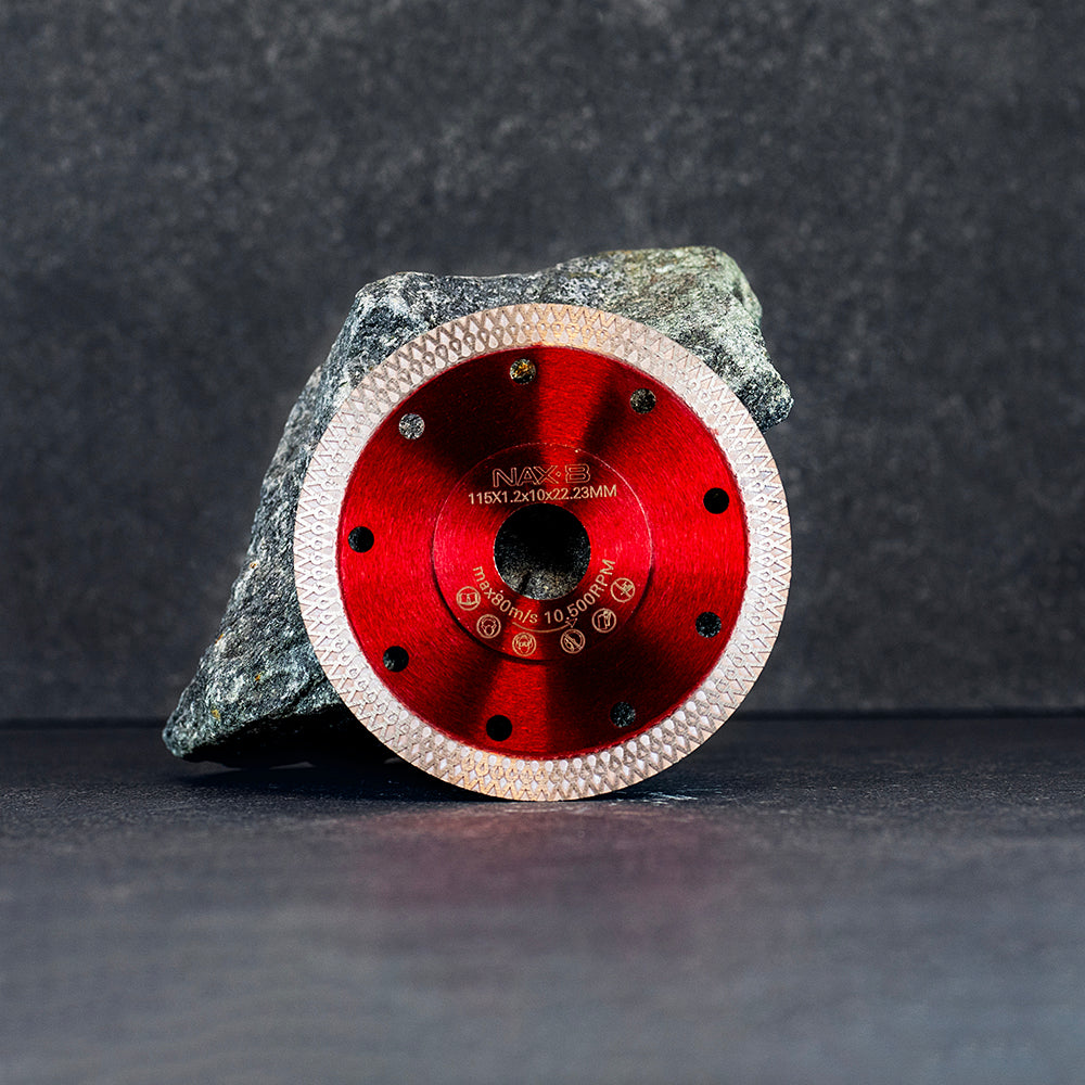 En röd diamantklinga från NAXB 115 mm lutandes mot en sten, mörk klinkerbakgrund