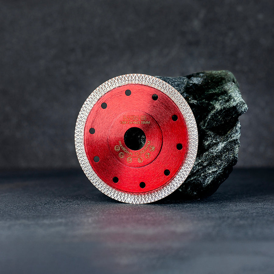 En röd diamantklinga från NAXB 125 mm lutandes mot en sten, mörk klinkerbakgrund