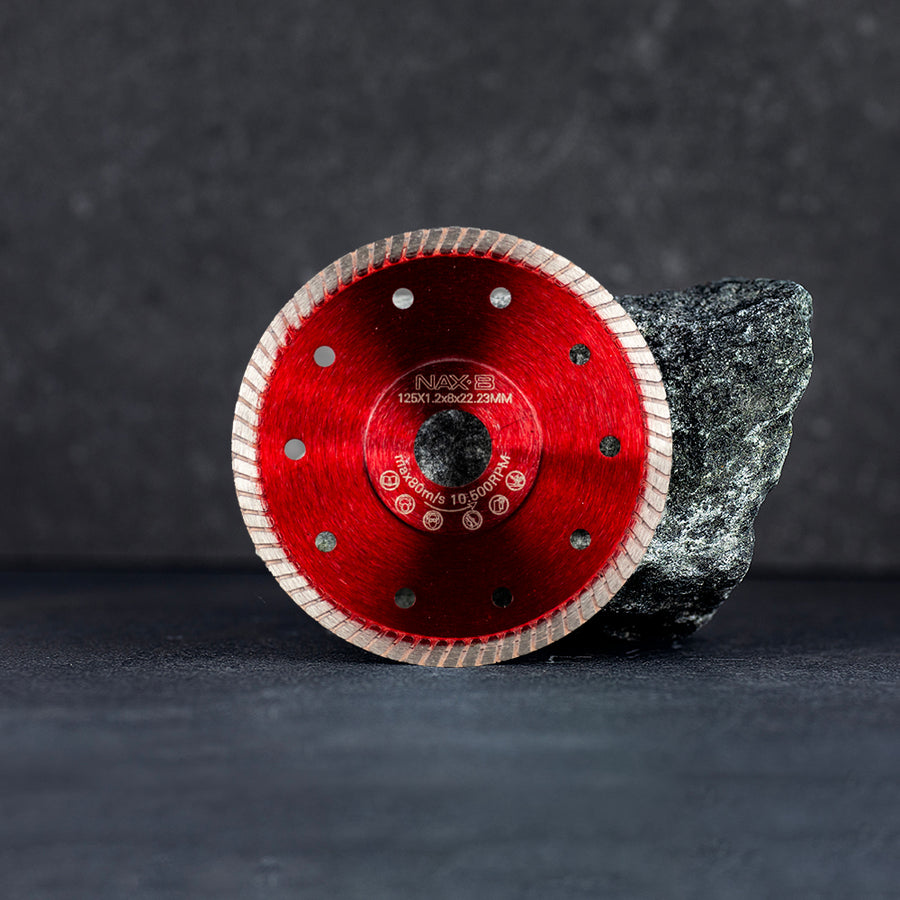 En röd diamantklinga 125 mm ståendes lutad mot en sten, mörk klinkerbakgrund