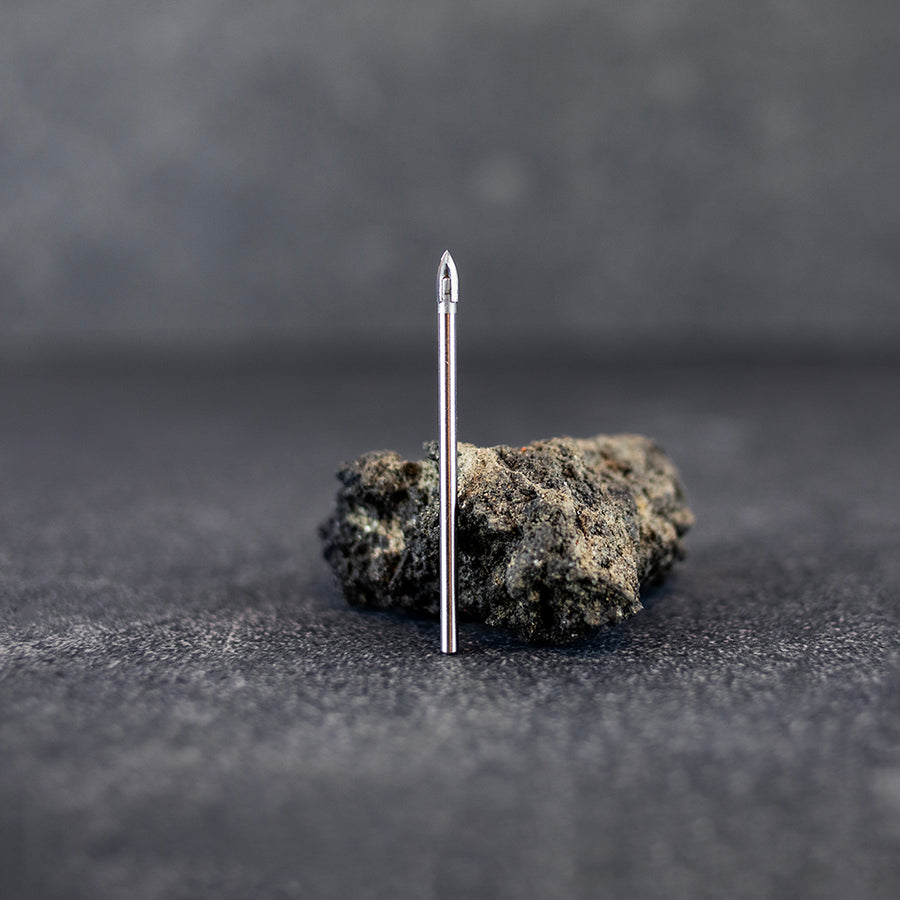 Ett kakelborr 4 mm som står upp framför en mindre sten, mörk klinkerbakgrund