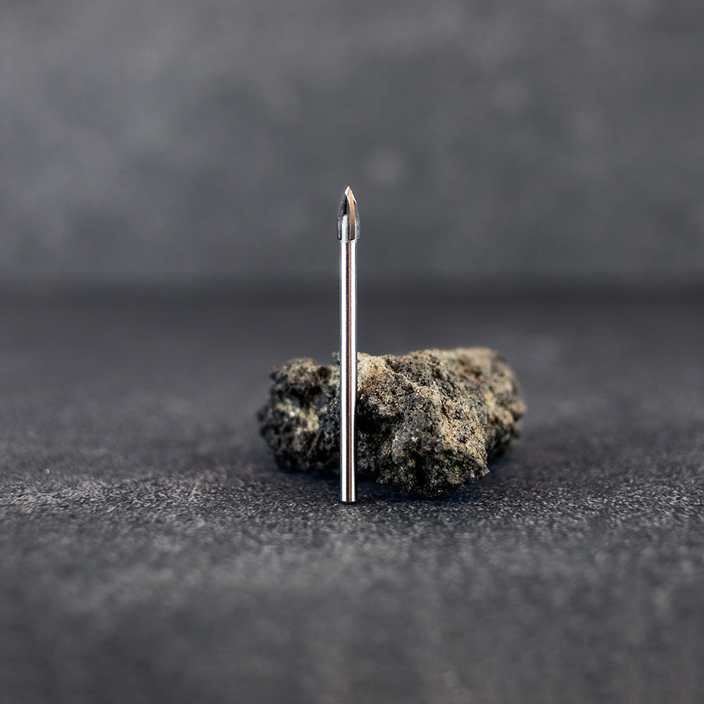 Ett kakelborr 5,5 mm som står upp framför en mindre sten, mörk klinkerbakgrund