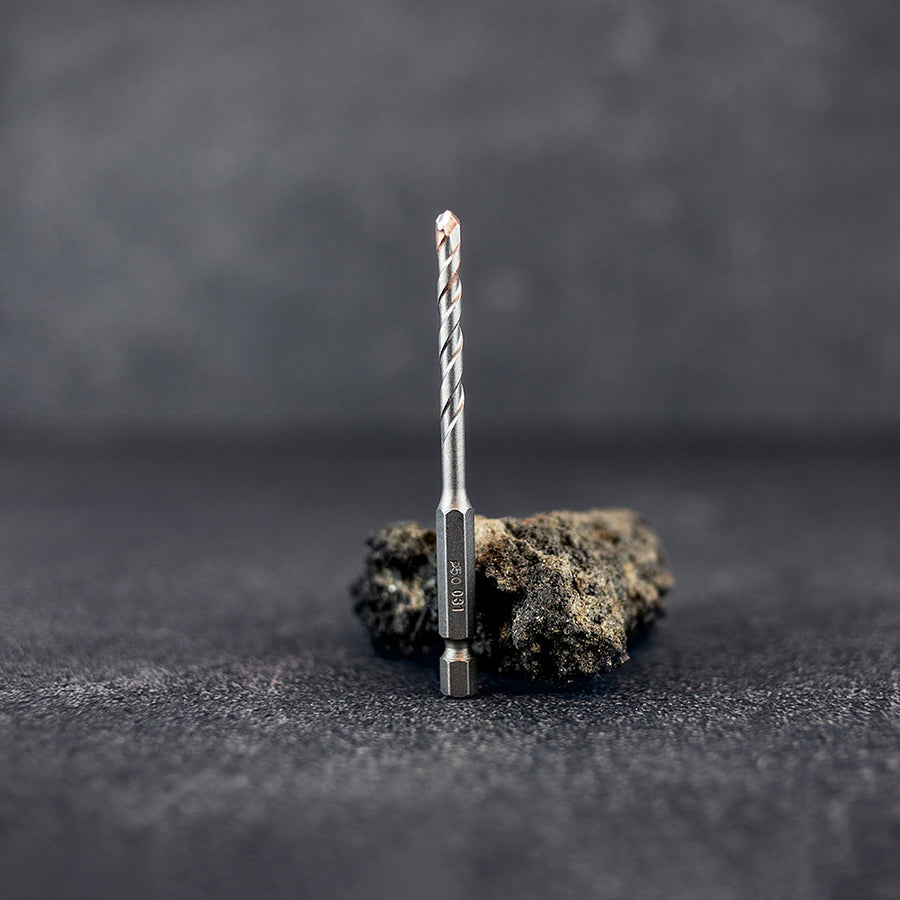 Ett klinkerborr 5 mm som står rakt upp framför en mindre sten, mörk klinkerbakgrund